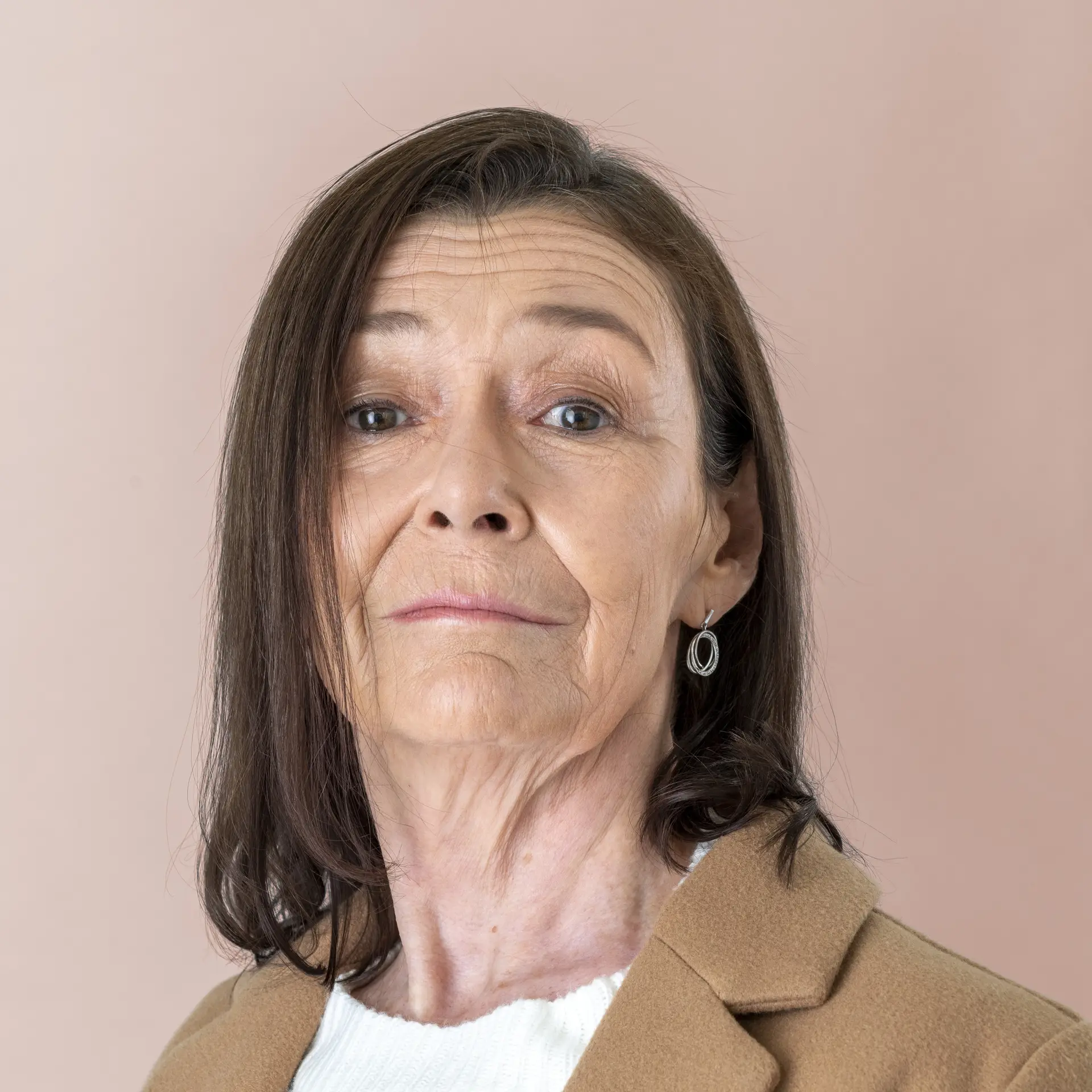 Foto de perfil de mujer de ~40 años, pelo recogido, blazer claro, fondo neutro, expresión serena.